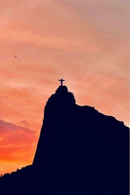 About 3 Silhouette of Christ the Redeemer statue on Corcovado Mountain in Rio de Janeiro at sunset.