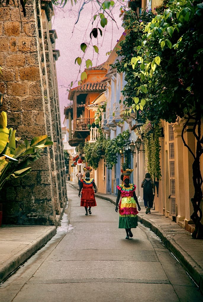 Our 5-Day Cartagena Adventure (Continued) 9 Palenqueras in colorful dresses walking through a colonial street in Cartagena’s historic walled city, Colombia.