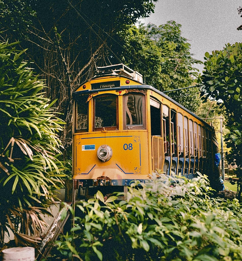 Trams and Trolleys of Latin America: Historic Rides Through Time 20 Yellow Santa Teresa tram in Rio de Janeiro surrounded by lush greenery, captured in an editorial panoramic hero banner format.